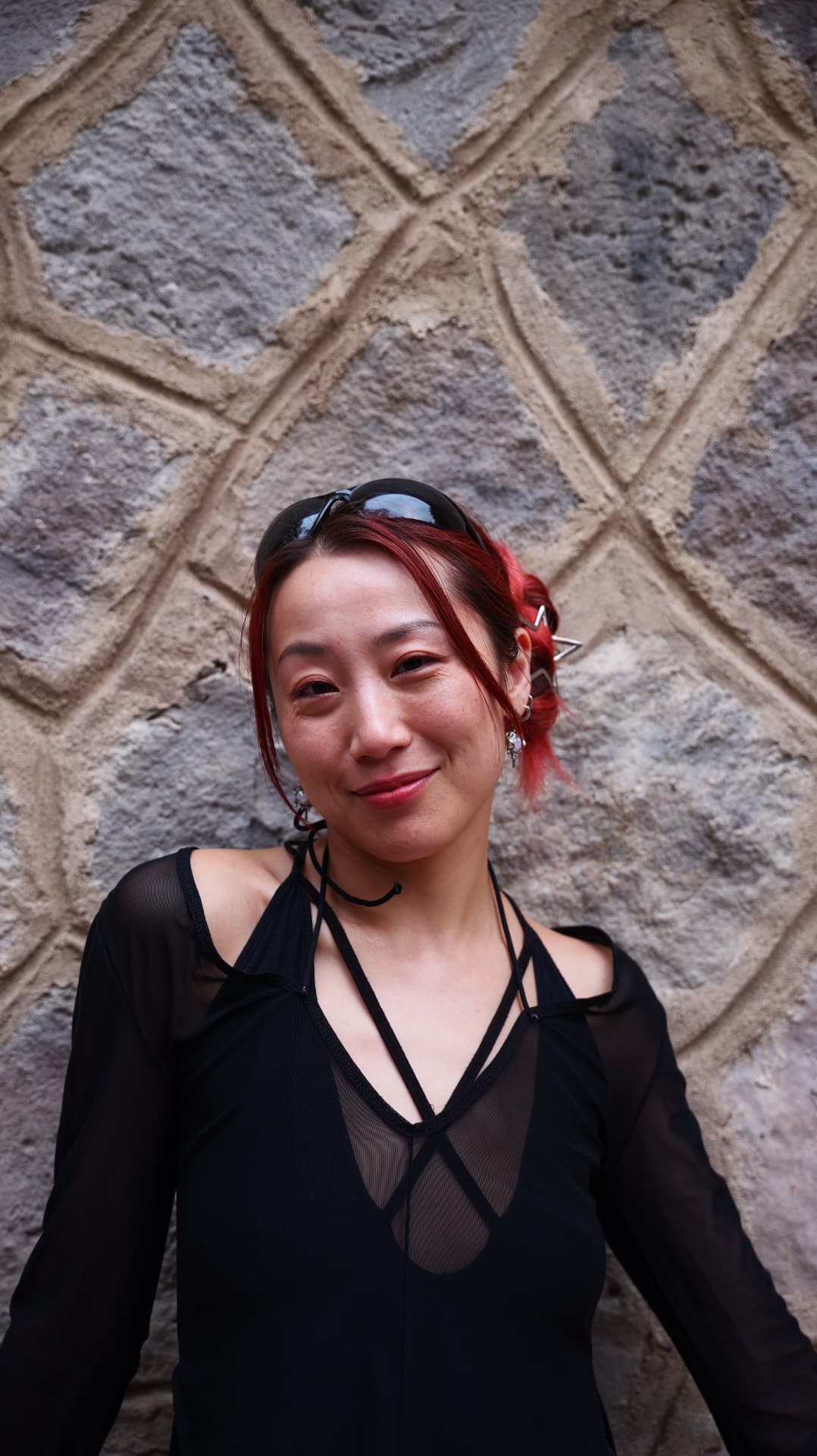 Smiling woman with red hair against a carved stone wall