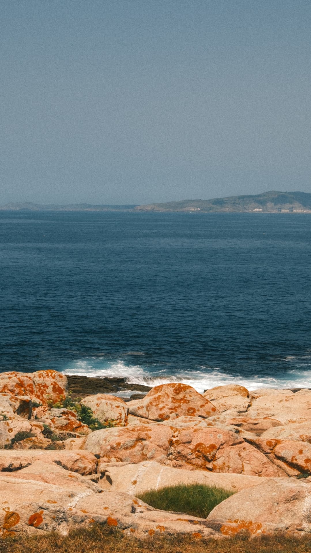 Orange lichen-covered rocks above the deep blue Atlantic in Galicia