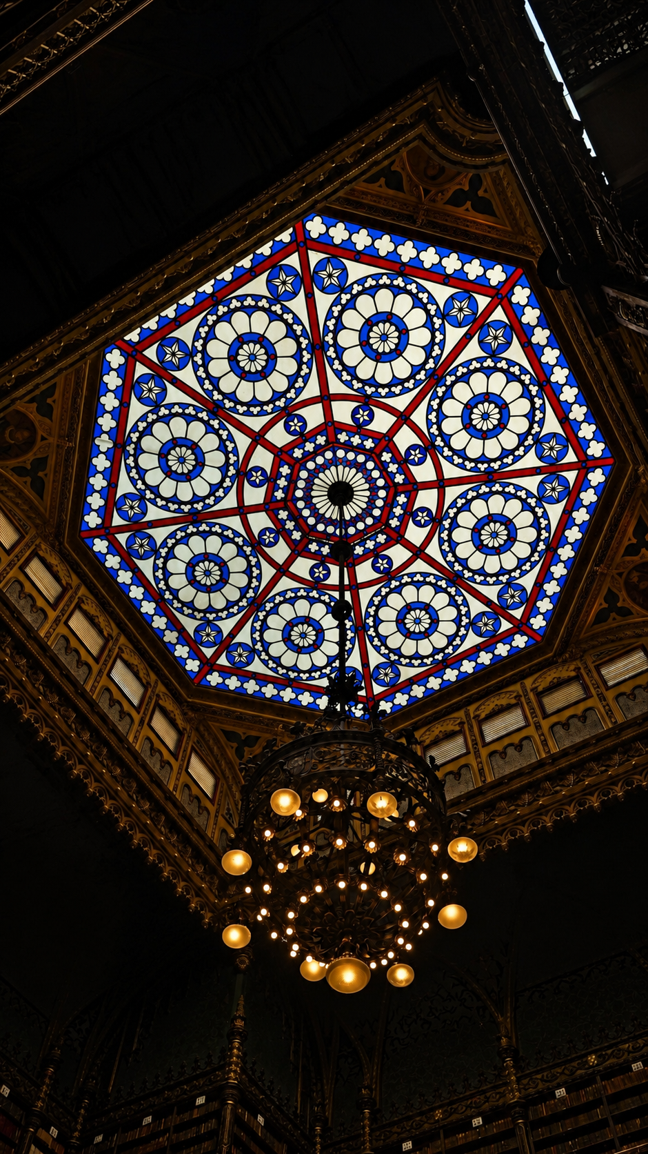 Octagonal stained-glass skylight glowing above the chandelier in the library reading room