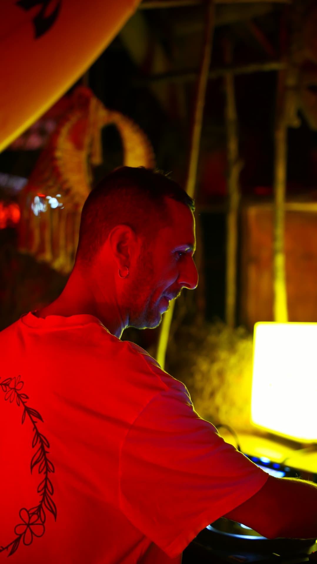 Profile of a DJ lit red against a warm yellow haze