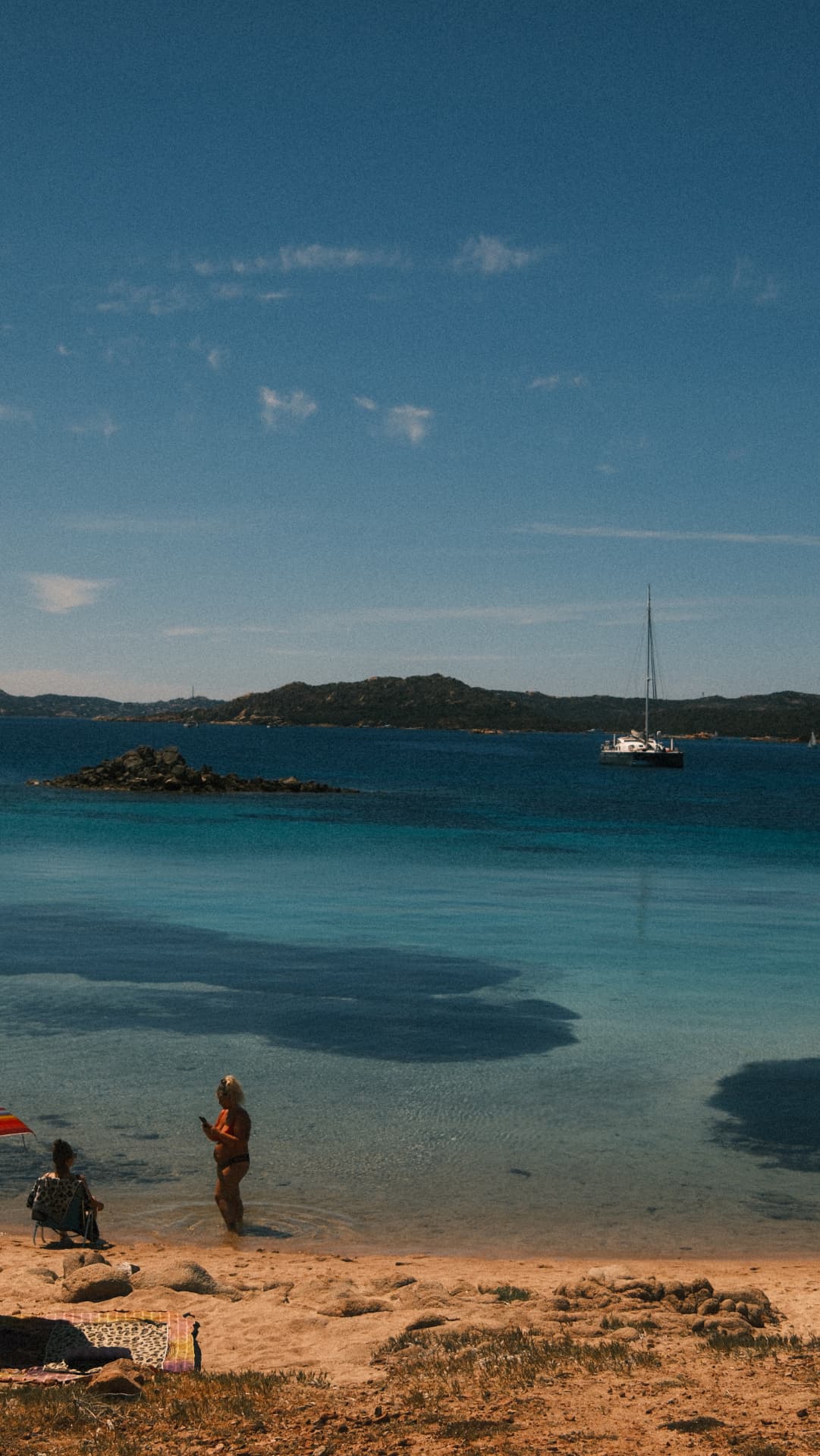 Turquoise bay with a moored catamaran and swimmers near the shore