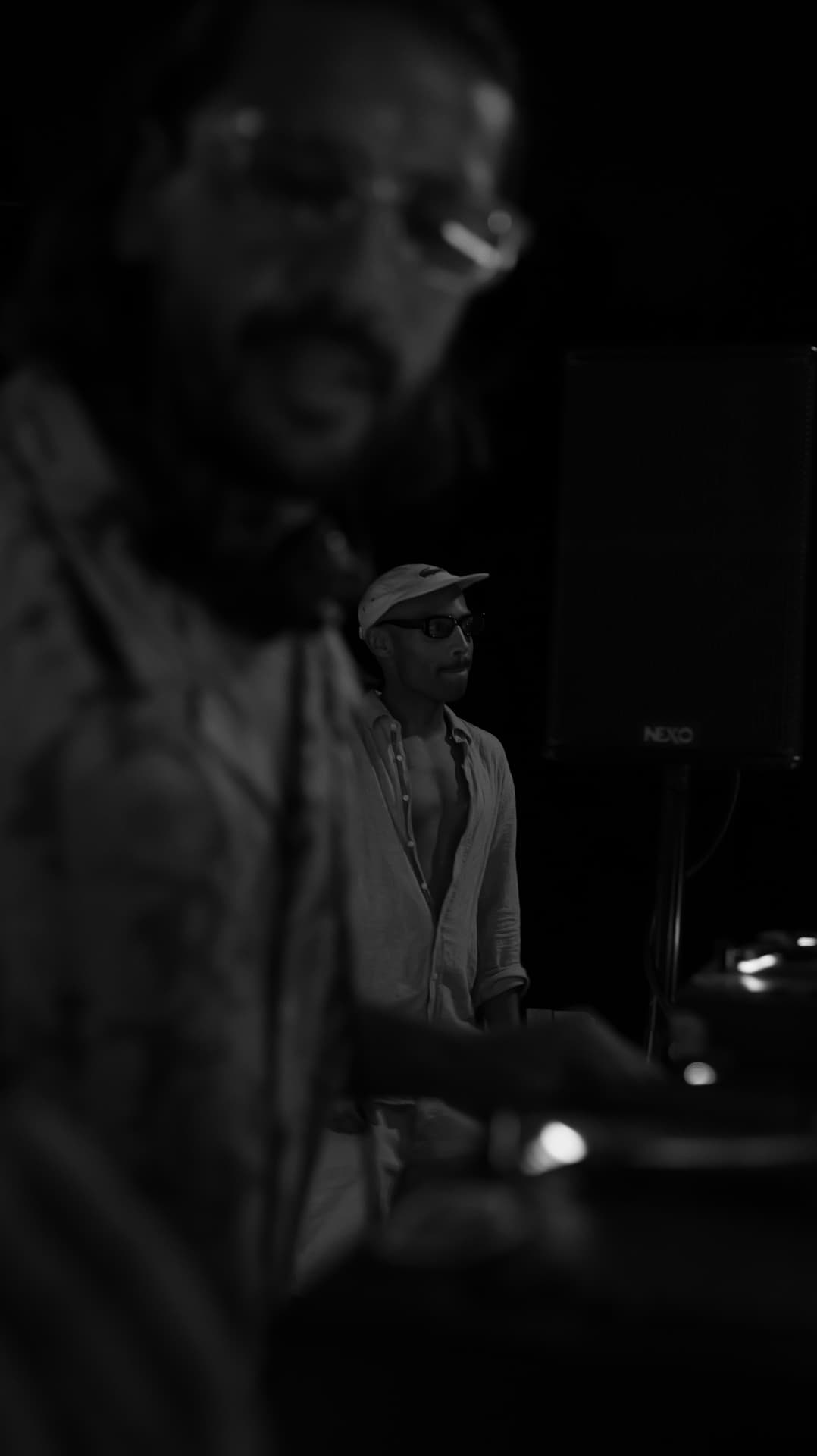 Black-and-white scene behind the decks with a speaker stack
