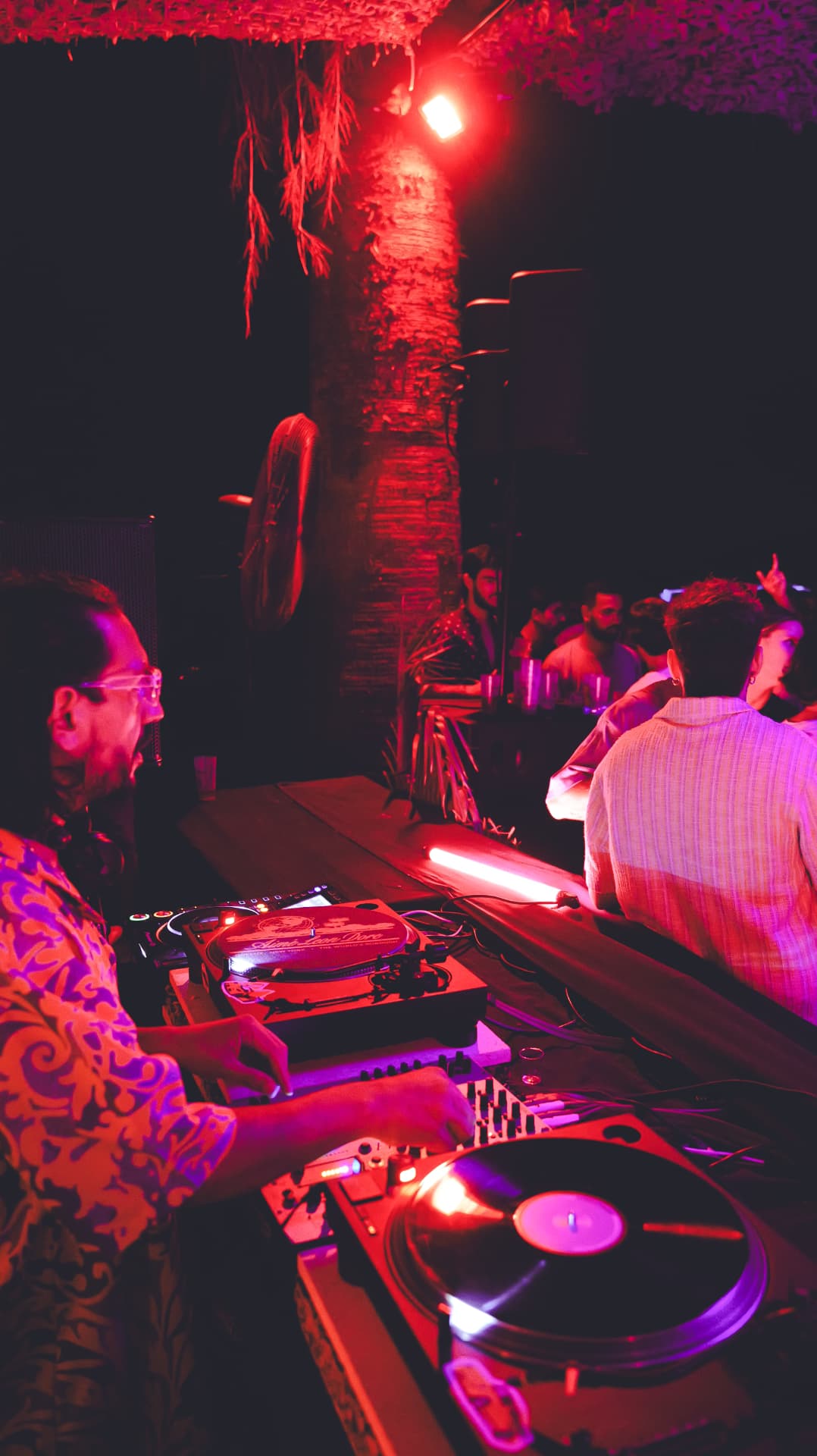 DJ mixing vinyl turntables in red and pink club light