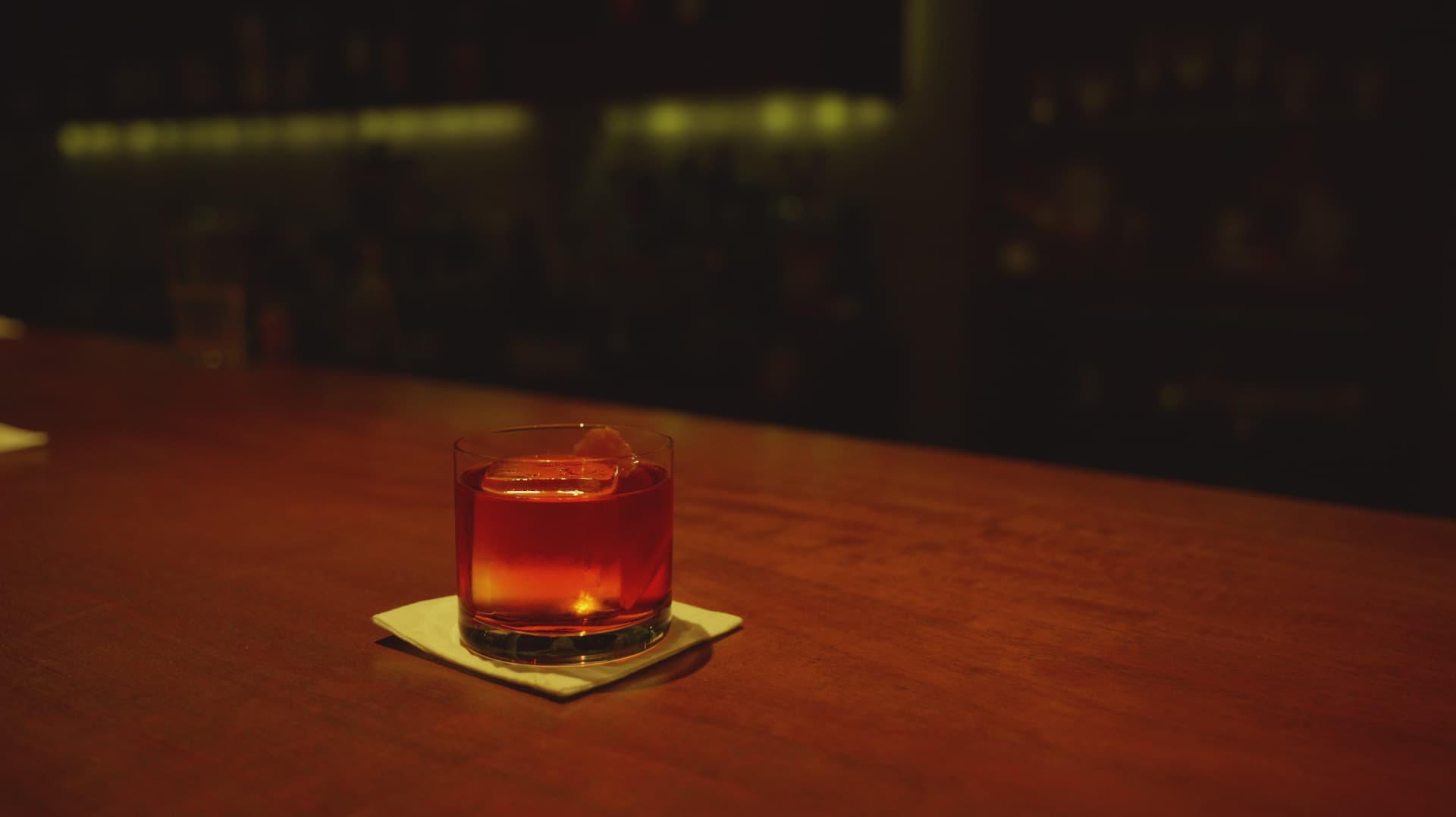 Red cocktail glowing on a polished bar in low light