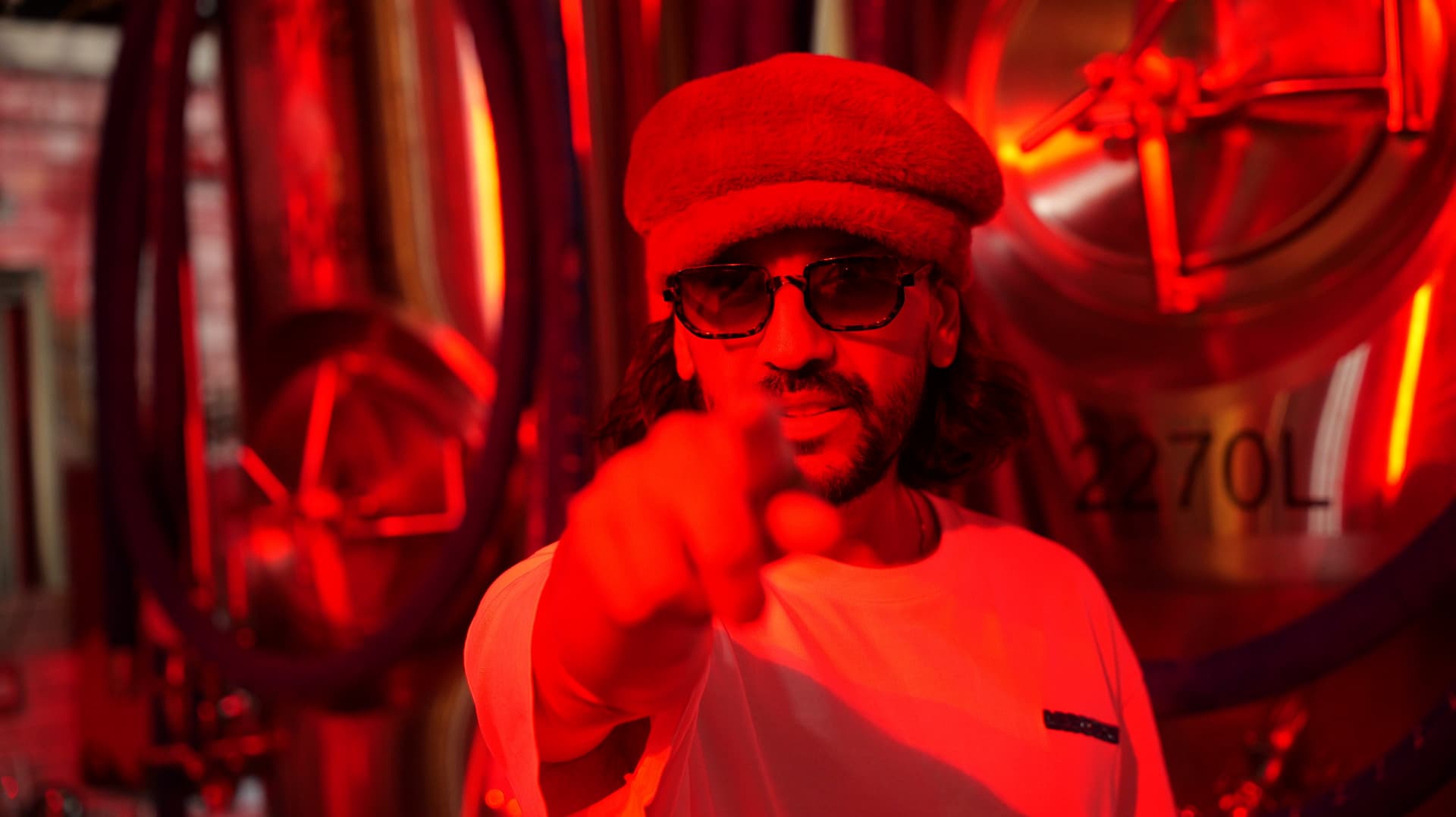 Man in a beret pointing at the camera in red brewery light