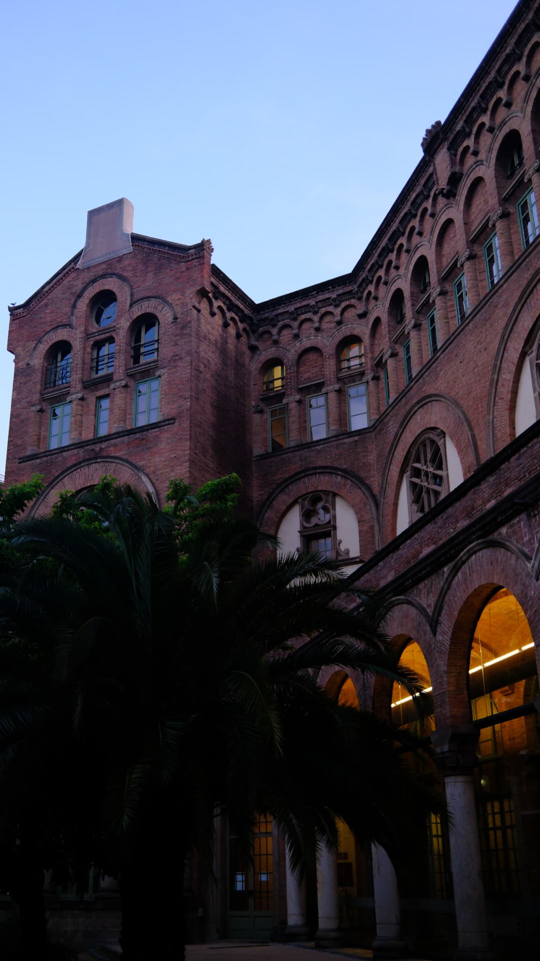 Red-brick Catalan modernista building with arched galleries at dusk