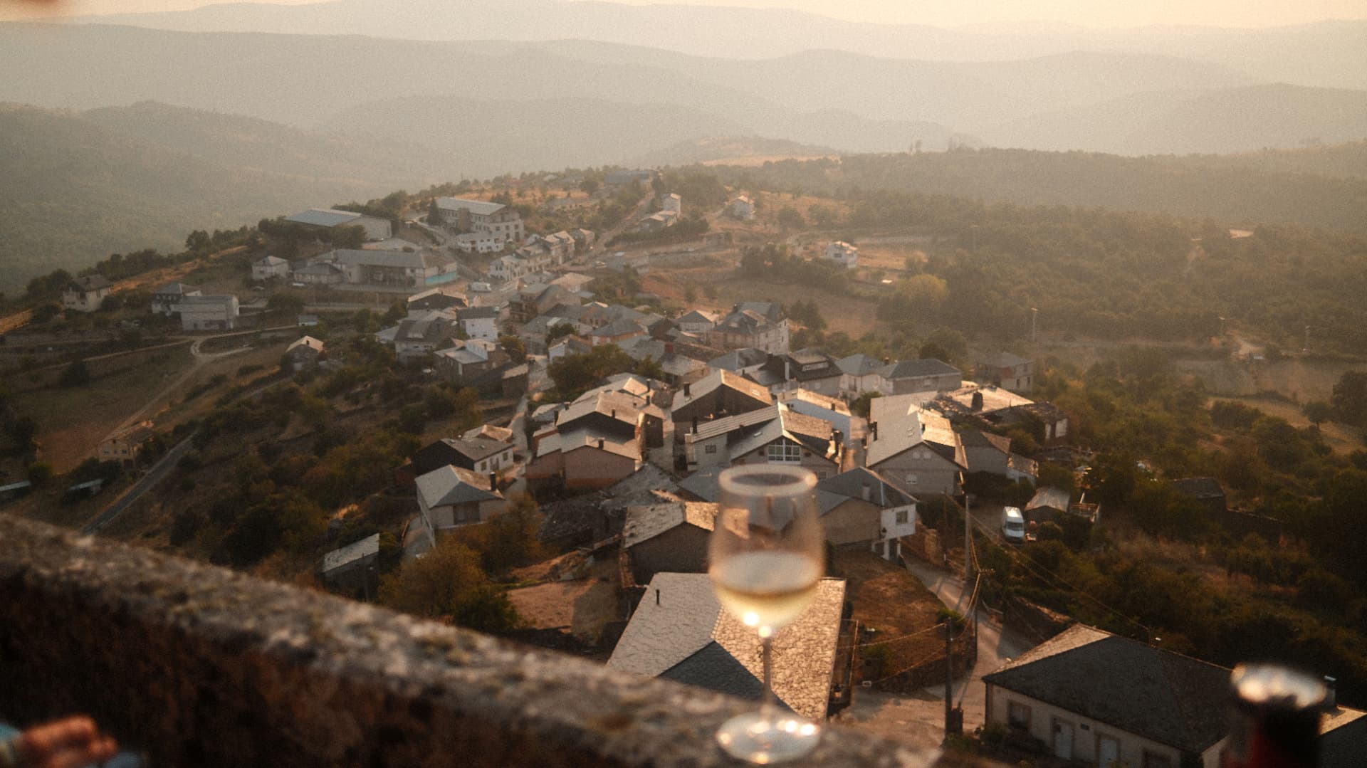 Mountain village glowing in warm evening light with a glass on a stone wall