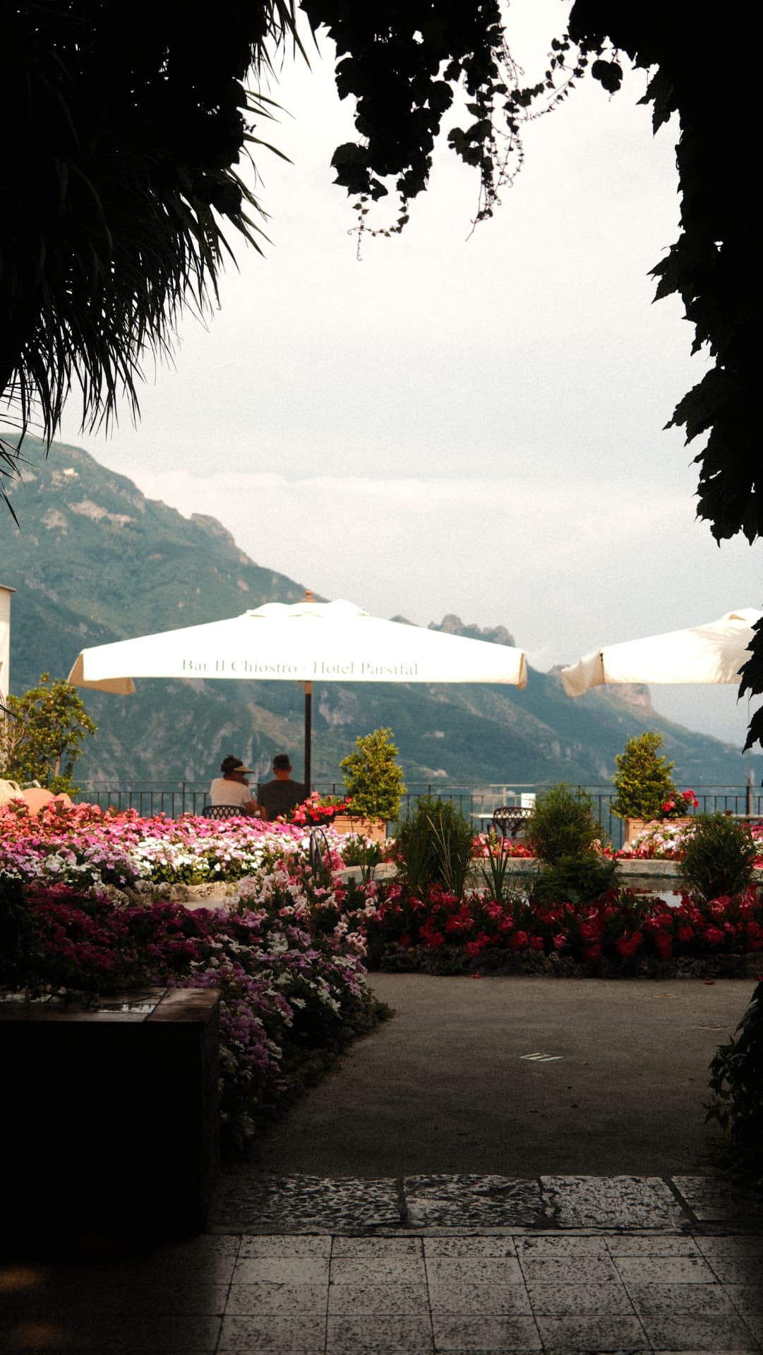 Flower-filled terrace garden with parasols looking out to the Amalfi mountains
