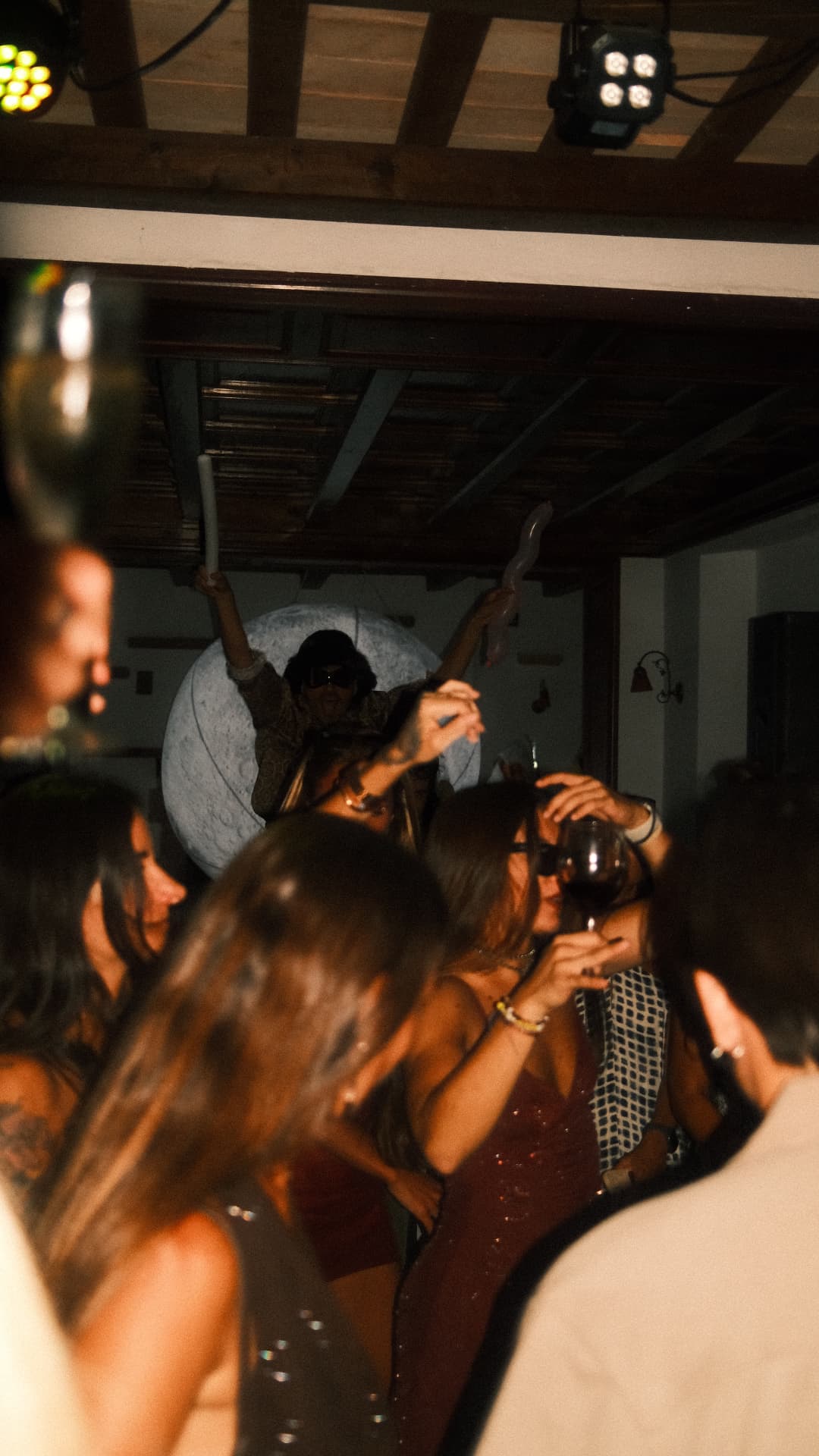 Crowd dancing under warm party lights with a disco ball overhead