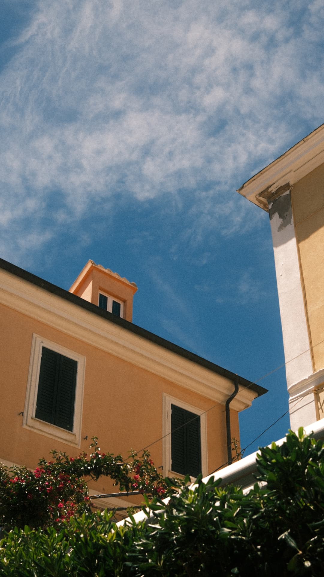 Ochre Italian houses with green shutters against a blue summer sky