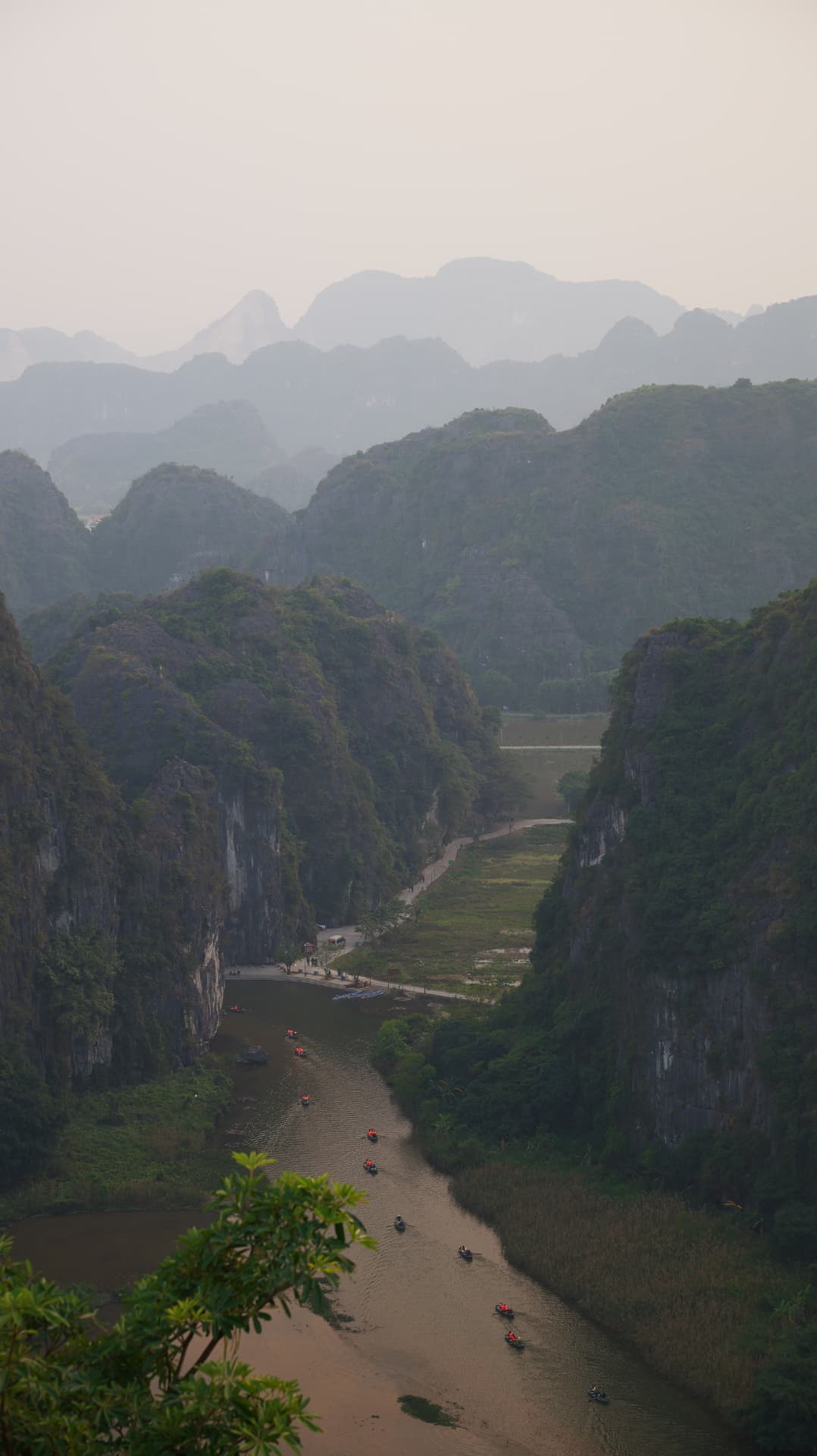 Rowing boats on a river winding between misty karst peaks in Ninh Binh