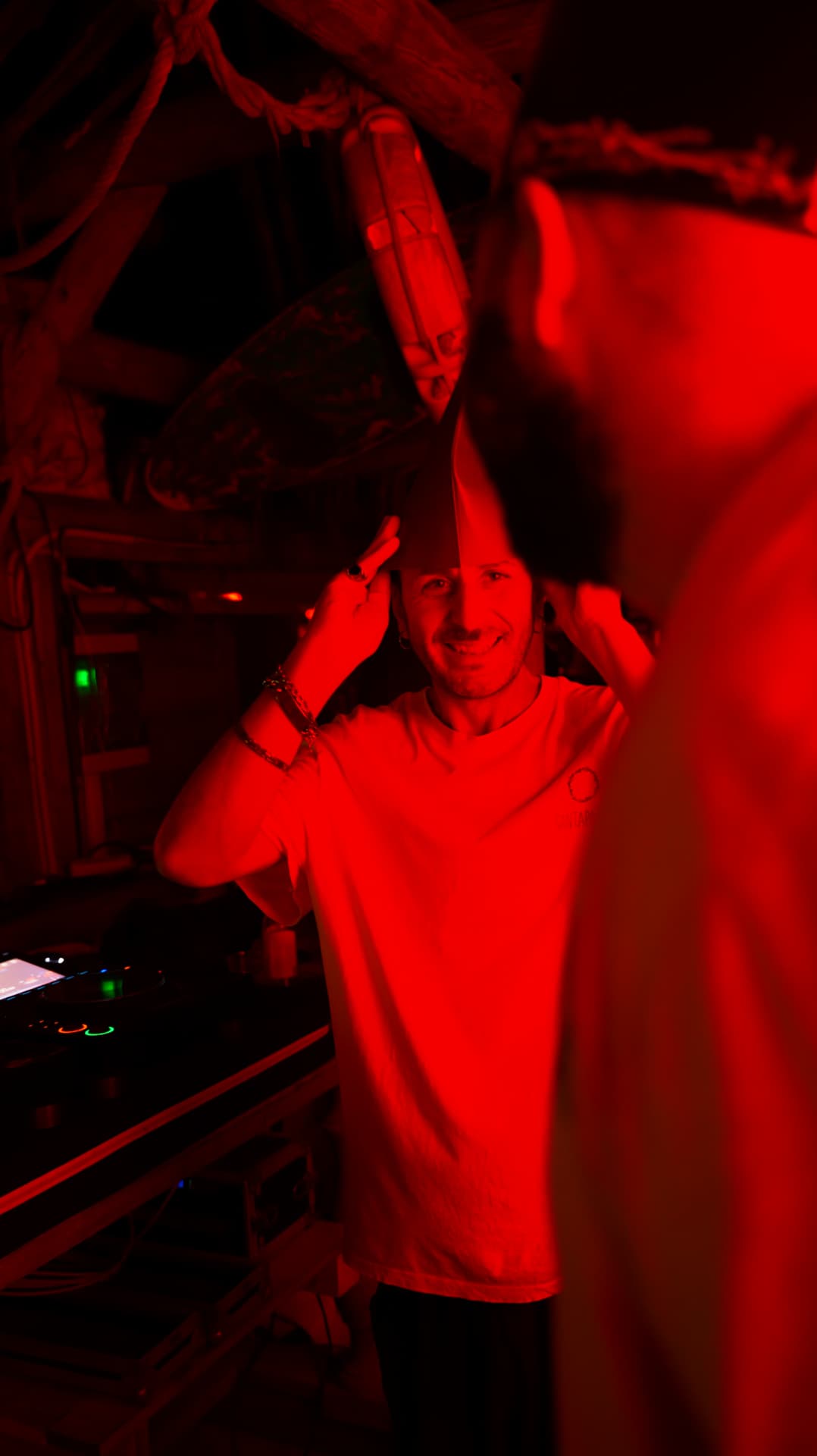 Smiling DJ holding a surfboard overhead in red light