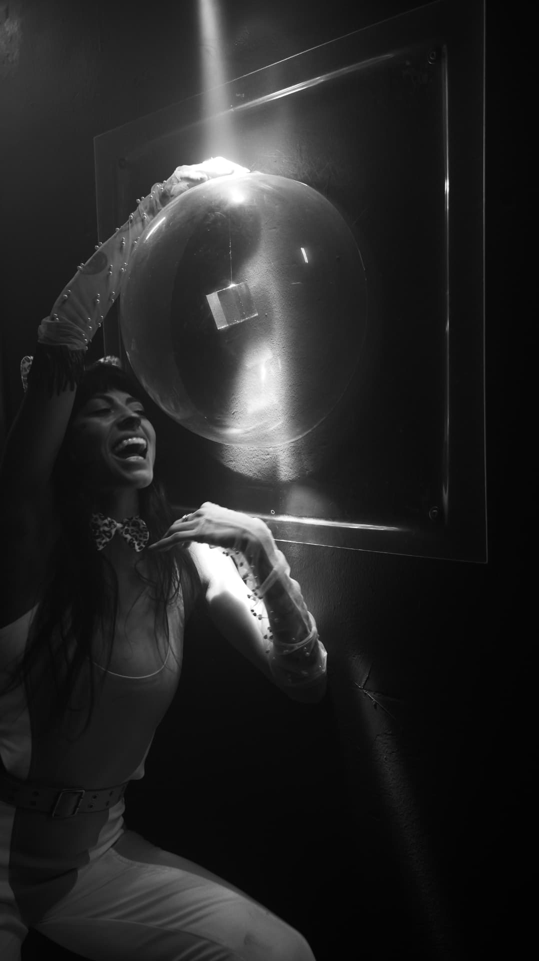 Black and white portrait of a laughing woman lifting a giant glass bubble