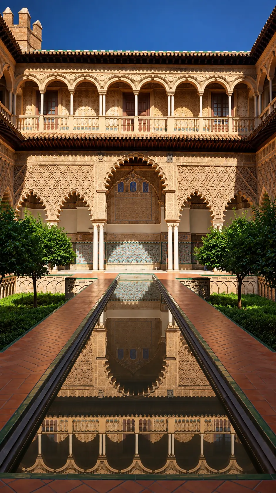 Moorish courtyard of the Alcázar of Seville reflected in a long pool