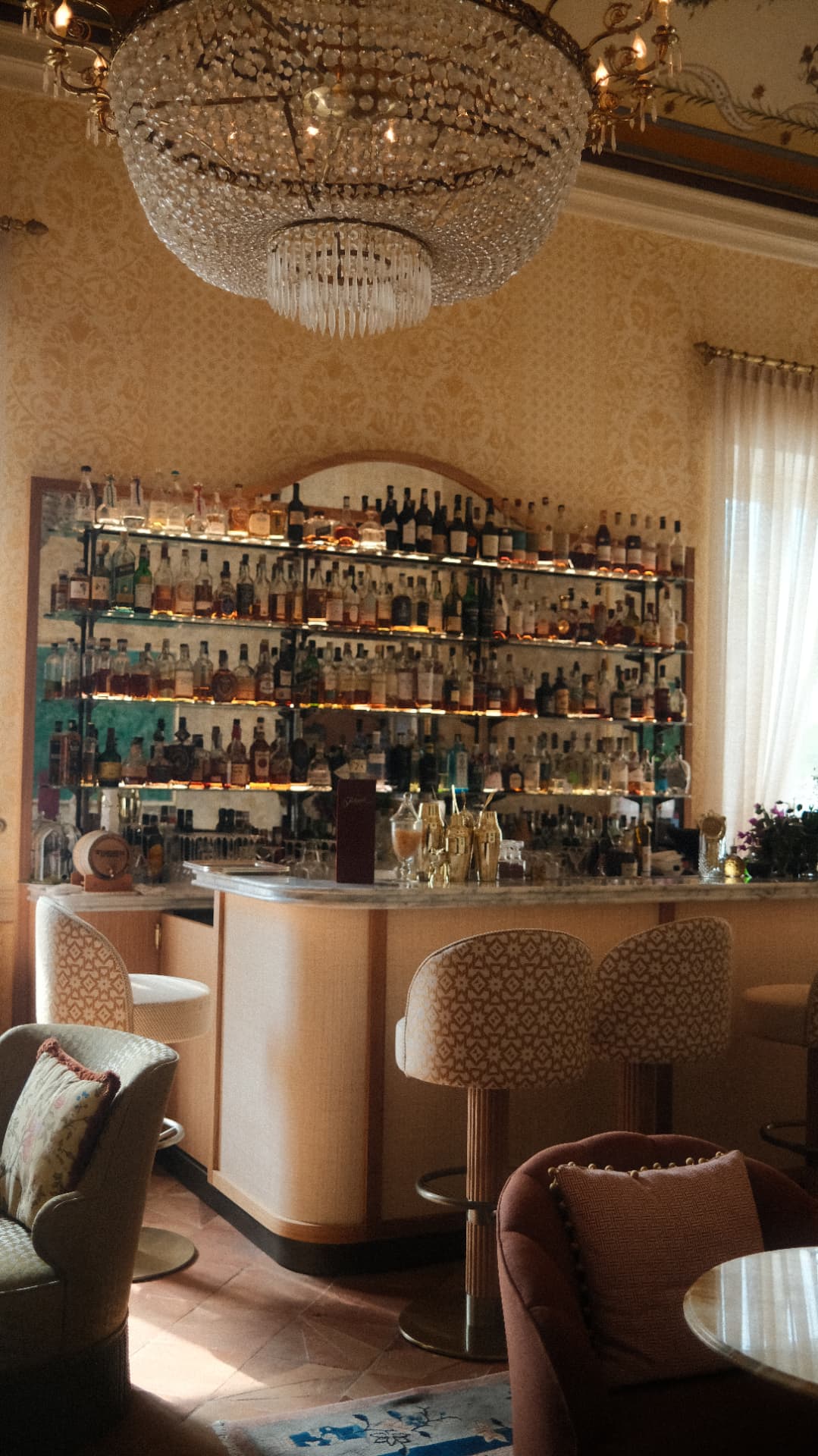 Chandelier above a bottle-lined hotel bar in soft golden light