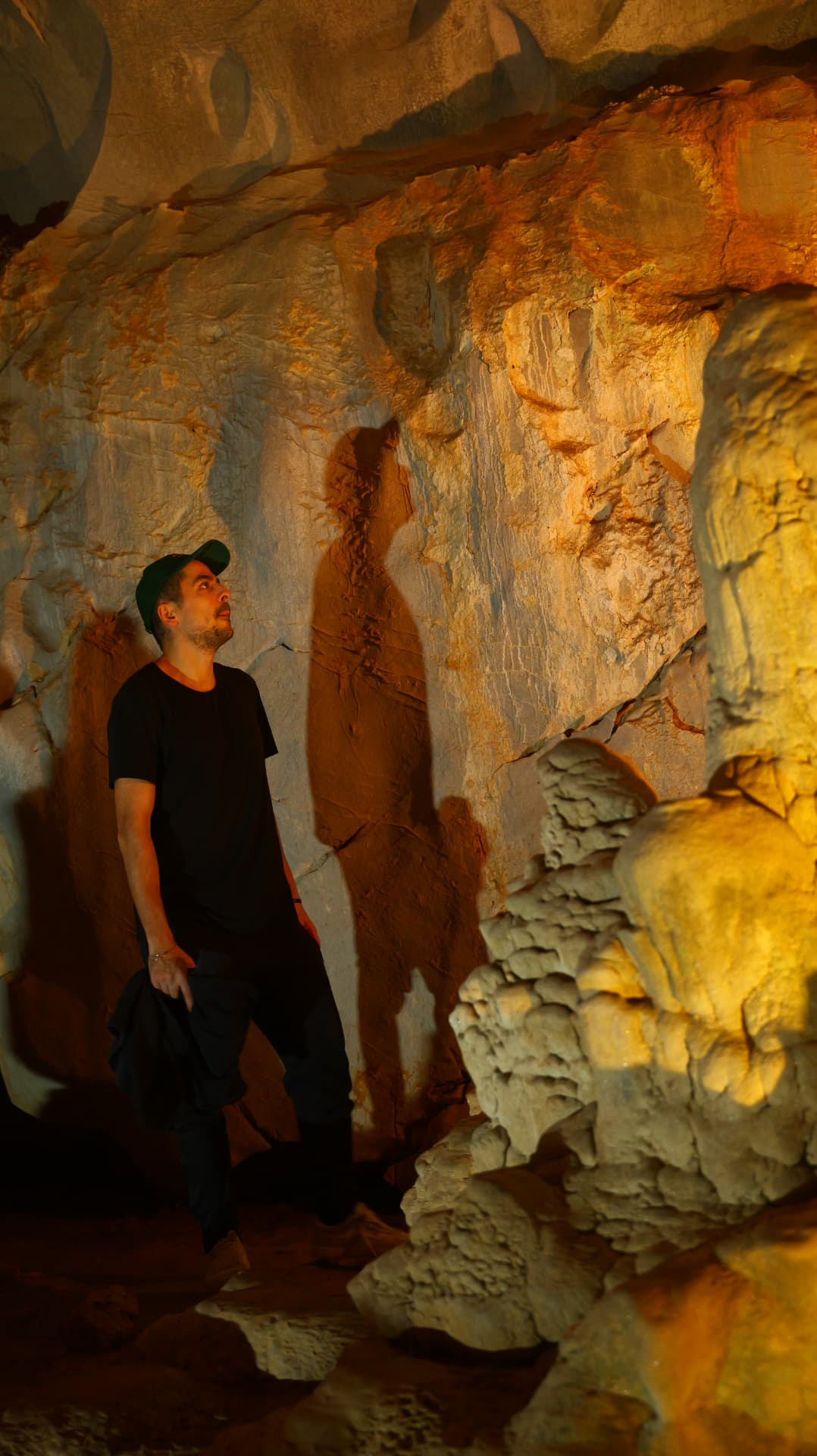 Alex observing illuminated rock formations inside a cave