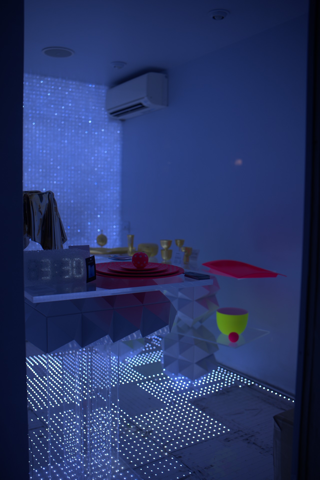 Blue-lit installation room with an LED curtain wall, fibre-optic floor and red and gold tableware