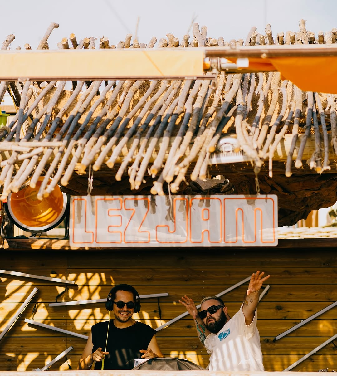 Lezzjam open-air booth — two DJs under a wooden canopy