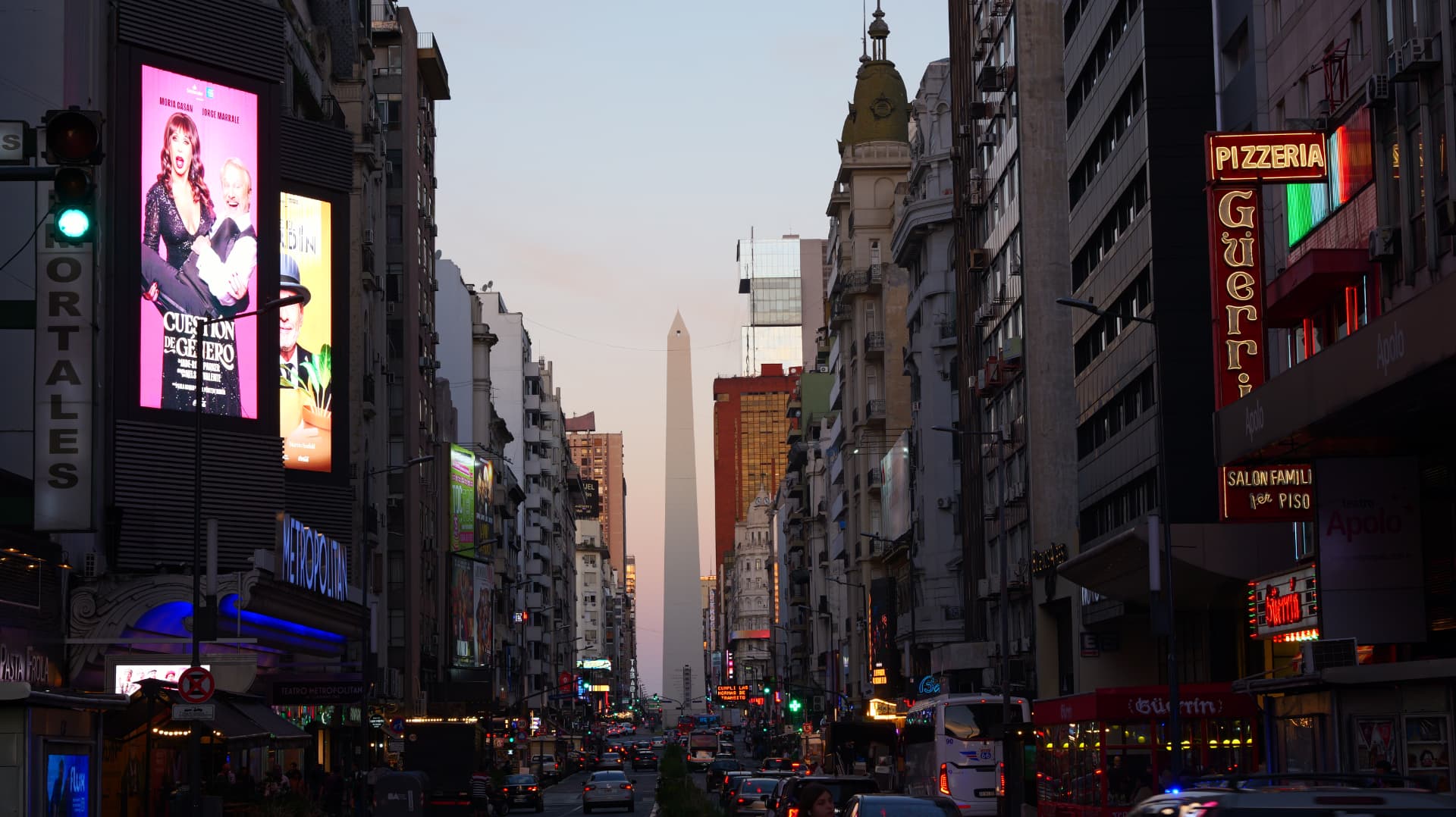 Buenos Aires avenue at dusk with neon signs and the Obelisco in the distance