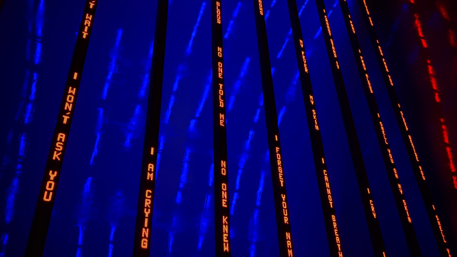 Red LED text panels glowing against a deep blue light installation