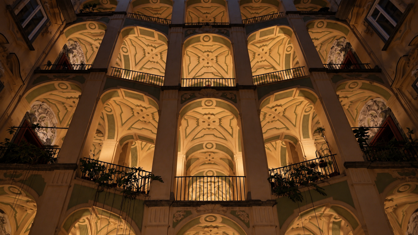 Illuminated frescoed arches and balconies of a Naples palace courtyard at night