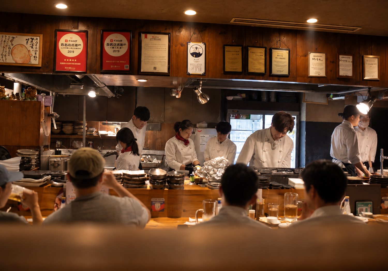 Chefs preparing food behind the counter of a warmly lit Japanese restaurant