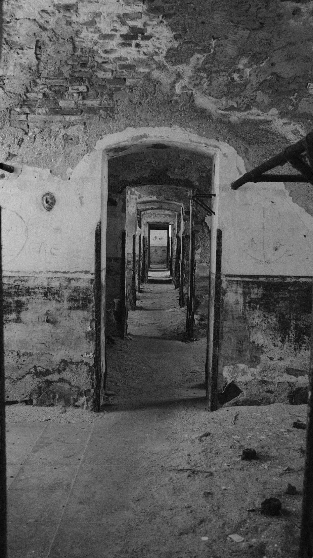 Black and white corridor of crumbling doorways in an abandoned building