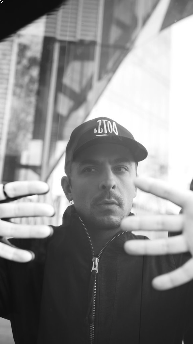 Black and white portrait of Alex Cristea in a cap, shot through glass