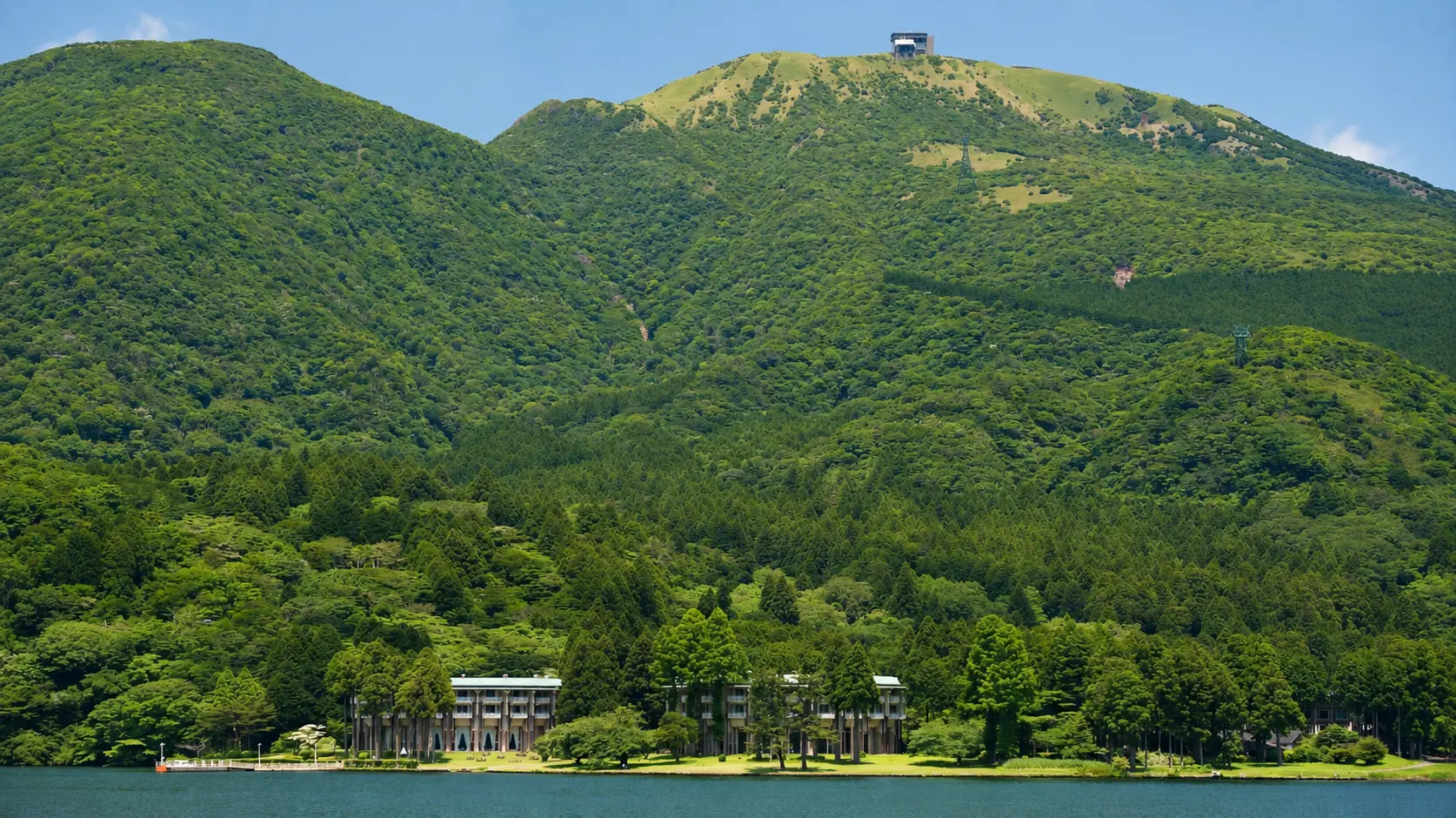 Green Hakone mountains rising above a calm blue lake beneath a clear sky