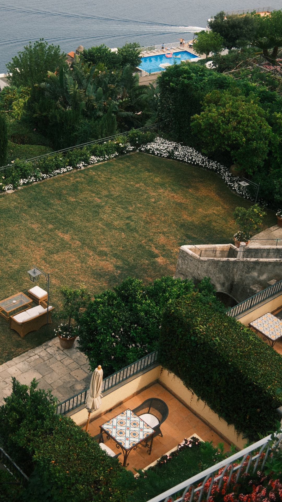 Cliffside garden, terraces and a pool seen from above with the sea beyond