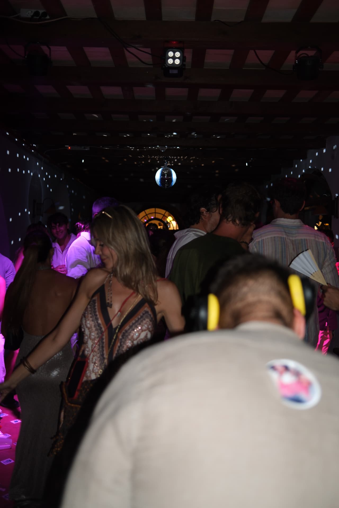 Dancers under a glittering disco ball and violet club lights